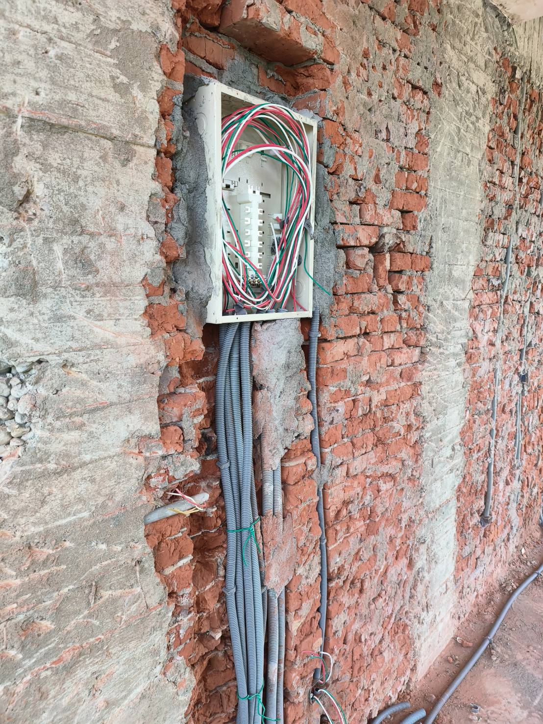 嵌入式白色配電箱內部整理：多色電線重新分路、灰色波紋導管整合。